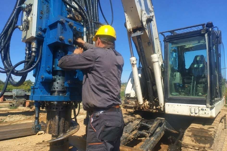 Tecnico monta attrezzatura di perforazione su telaio di escavatore